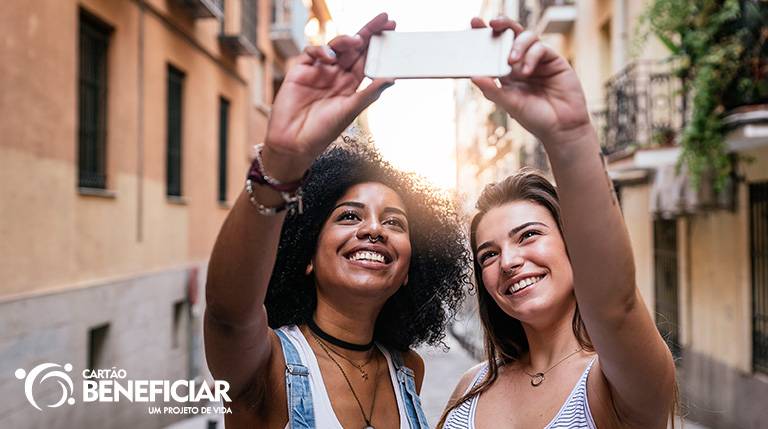 Mulheres felizes tirando fotos ao ar livre, mostrando a liberdade de um método seguro e de pouca manutenção como o DIU.