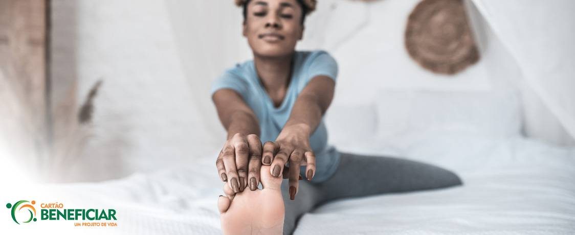 Mulher desfocada ao fundo, com o pé em primeiro plano, se alongando (o que é uma boa maneira de diminuir o formigamento nos pés).